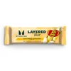Een verpakte Myprotein Layered Bar met de smaak 'buttered popcorn', met een afbeelding van Jelly Belly snoepjes.