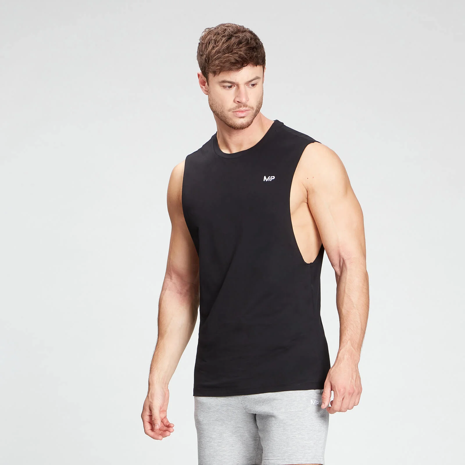Een man draagt een zwarte MP tanktop zonder mouwen, met het MP logo.
