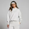 Een vrouw draagt een gemêleerd lichtgrijze oversized hoodie met capuchon en bijpassende joggingbroek.
