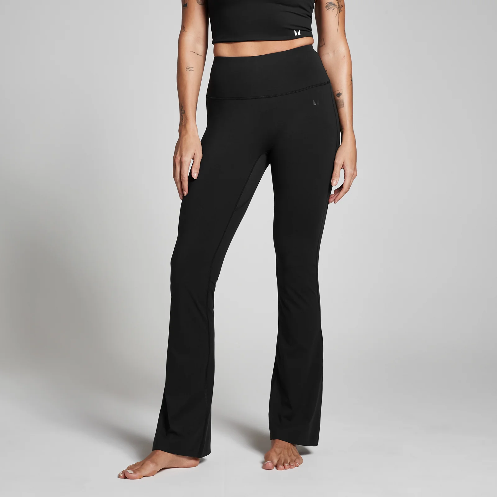 Zwarte legging met hoge taille en uitlopende pijpen, gedragen door een model.