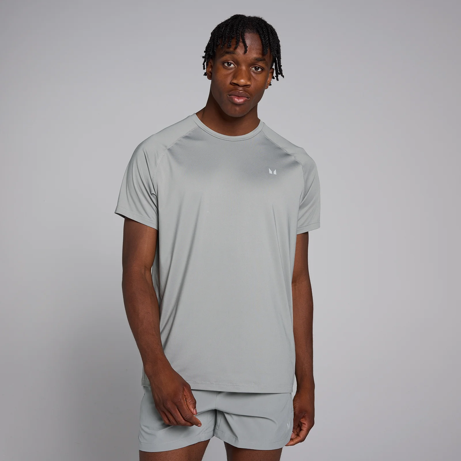 Een man draagt een stormgrijs trainingsshirt met korte mouwen en bijpassende korte broek.