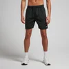 Een man draagt een zwarte, korte sportbroek met een elastische tailleband en witte sportschoenen.