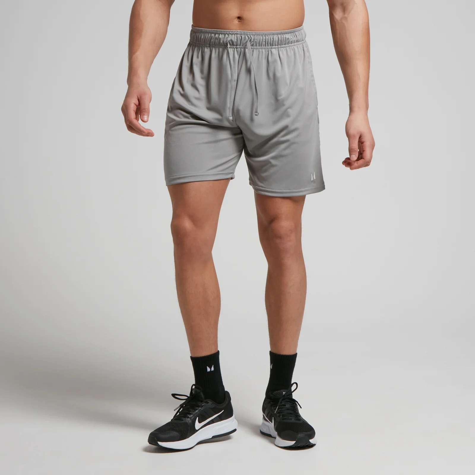 Een man draagt een stormgrijze, korte trainingsbroek met een elastische tailleband en een trekkoord.