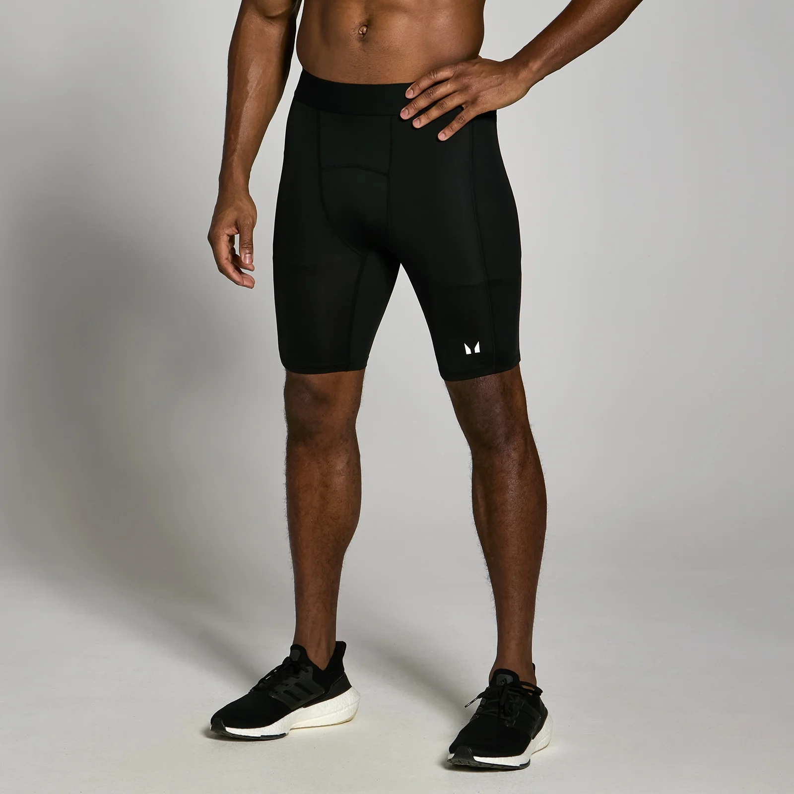 Een man draagt een zwarte, strakke trainingsshort met een elastische tailleband en een klein logo.