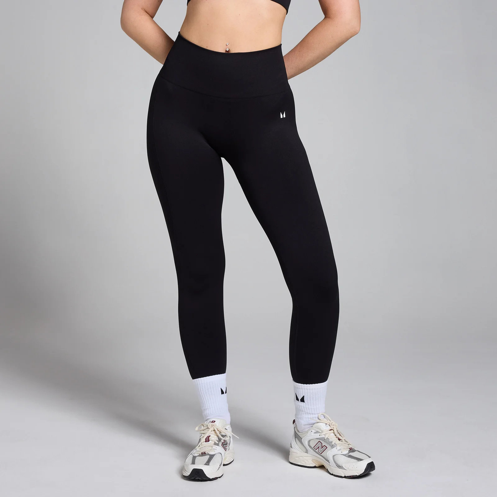 Een vrouw draagt een zwarte, naadloze legging met een hoge taille en een klein logo.