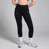 Een vrouw draagt een zwarte, naadloze legging met een hoge taille en een klein logo.