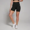 Een vrouw draagt een zwarte, naadloze fietsshort met een hoge taille en witte sportschoenen.