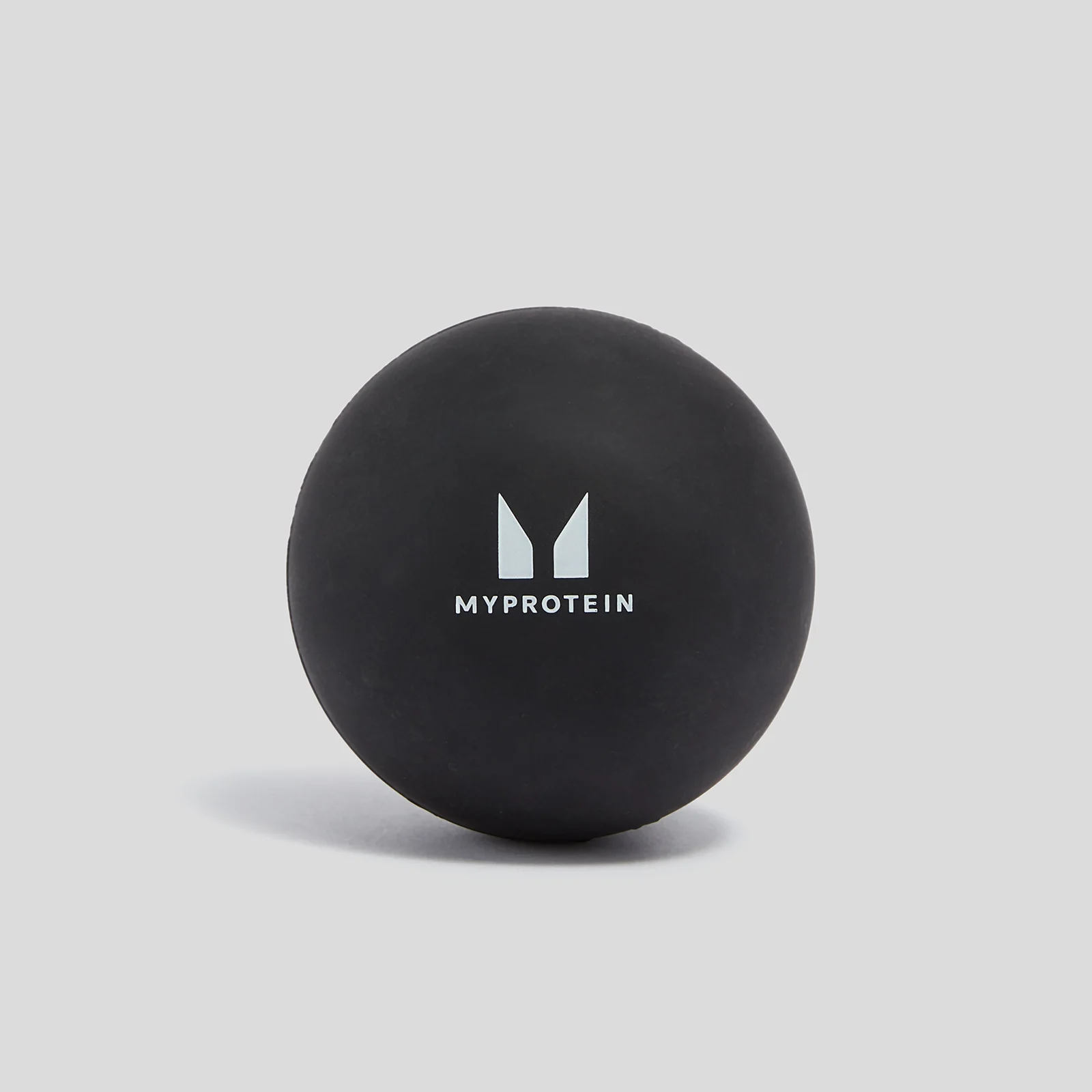Zwarte, ronde massagebal met het witte Myprotein logo erop, tegen een grijze achtergrond.