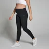 Een zwangere vrouw draagt een zwarte, middelhoge zwangerschapslegging en witte sportschoenen.