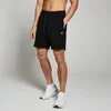 Een man draagt zwarte jogging shorts met een wit logo en witte sportschoenen.