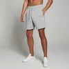 Een man draagt een gemêleerde grijze MP joggingbroek met witte sneakers.