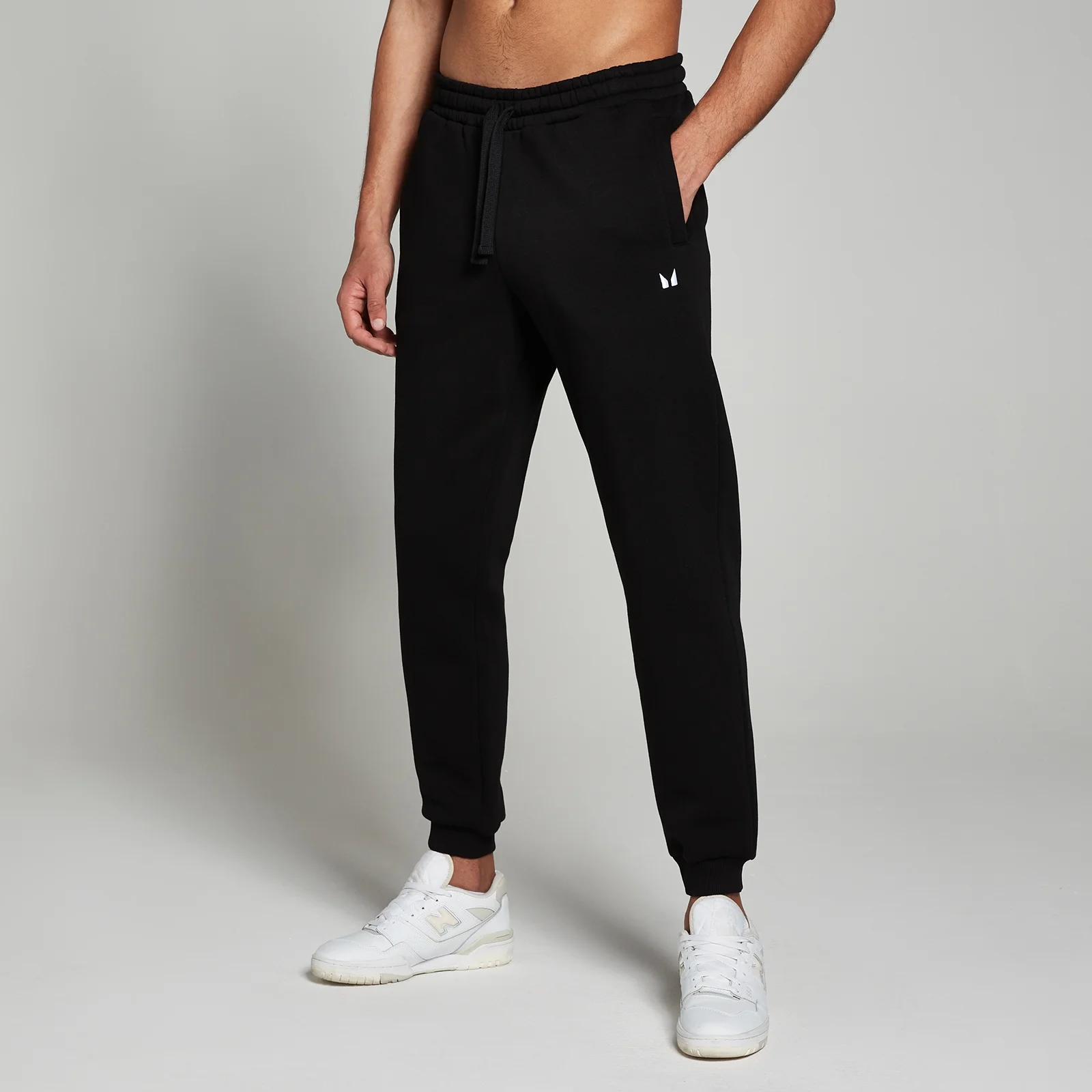 Een zwarte joggingbroek met trekkoord en een klein wit logo op de heup.