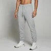 Een man draagt een gemêleerd grijze joggingbroek met trekkoord en witte sportschoenen.