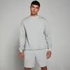 Een man draagt een gemêleerd grijs sweatshirt en bijpassende korte broek met een klein wit logo.