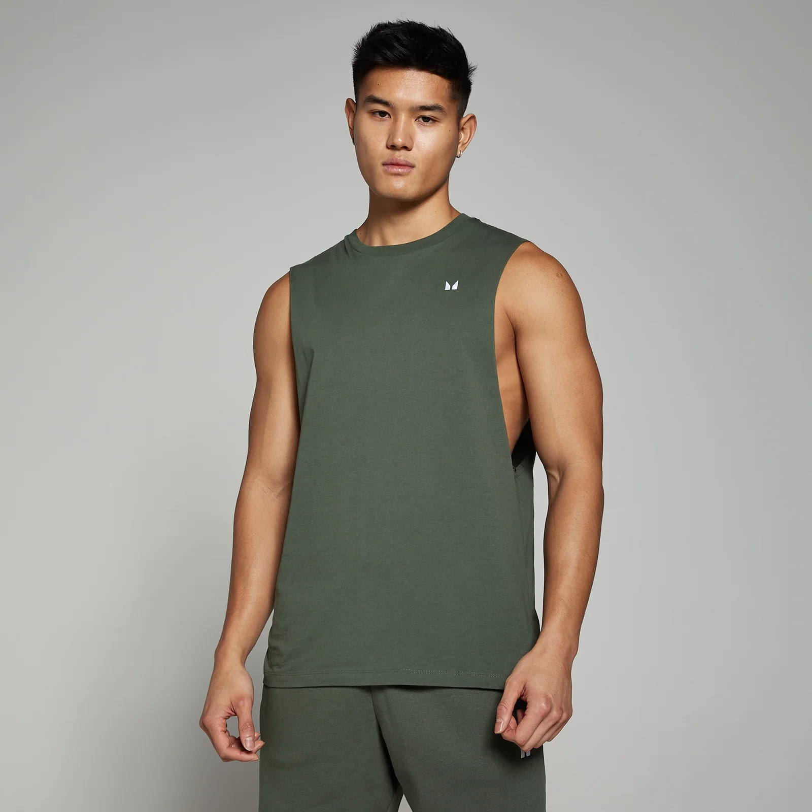 Een man draagt een thijmgroene mouwloze top met een klein wit logo.