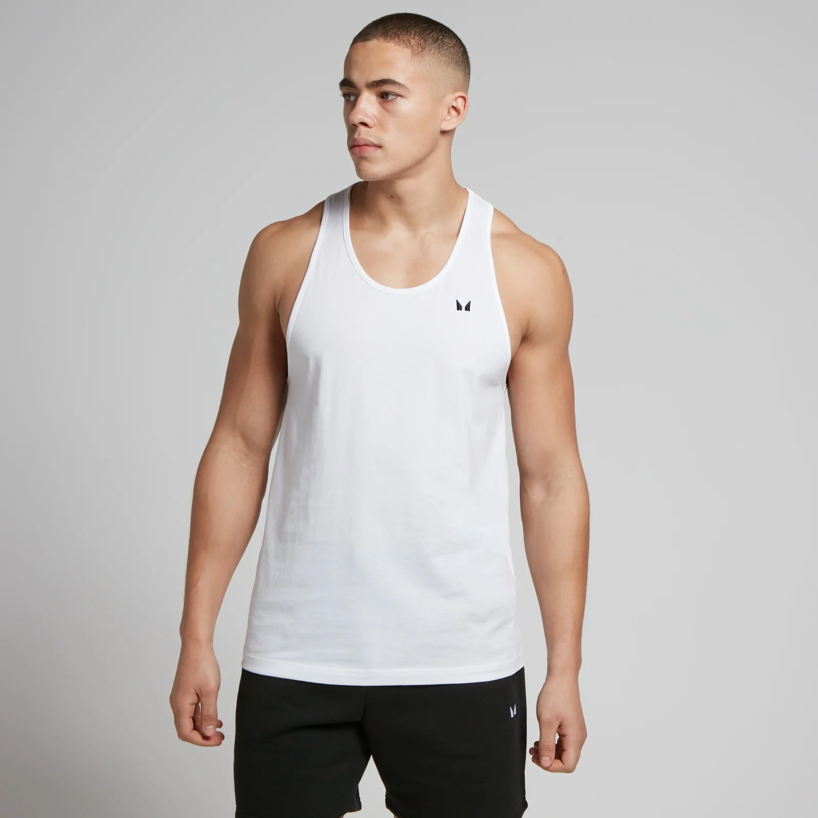 Een man draagt een wit hemd met halternek en een klein zwart MP logo.