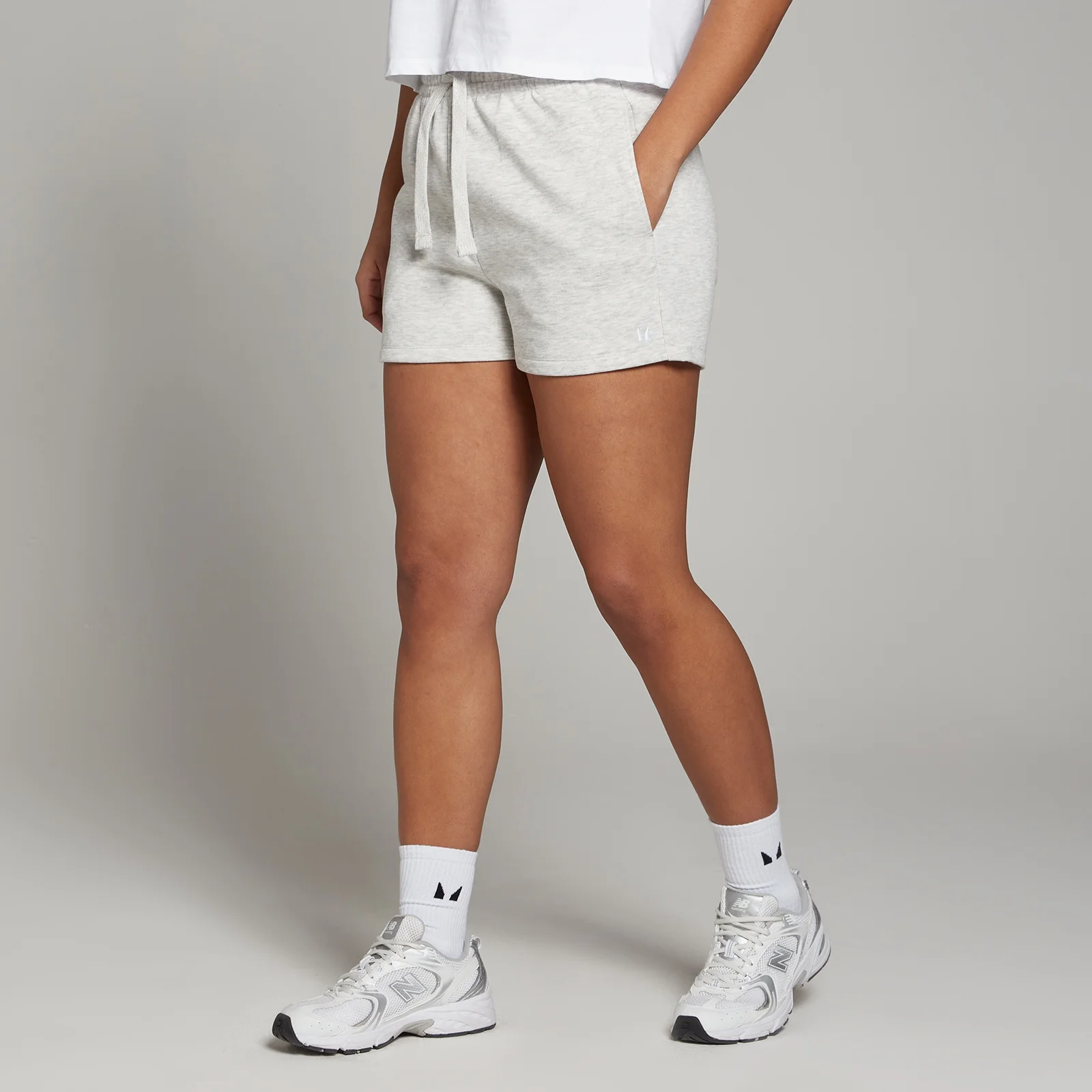 Een dame draagt gemêleerde lichtgrijze MP shorts met trekkoord en zakken.