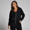 Een vrouw draagt een zwarte hoodie met rits en een klein wit logo.