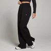Een vrouw draagt een zwarte joggingbroek met rechte pijpen en een klein wit logo.