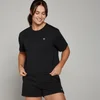 Een vrouw draagt een zwarte croptop met korte mouwen en een losse pasvorm, samen met een zwarte korte broek.