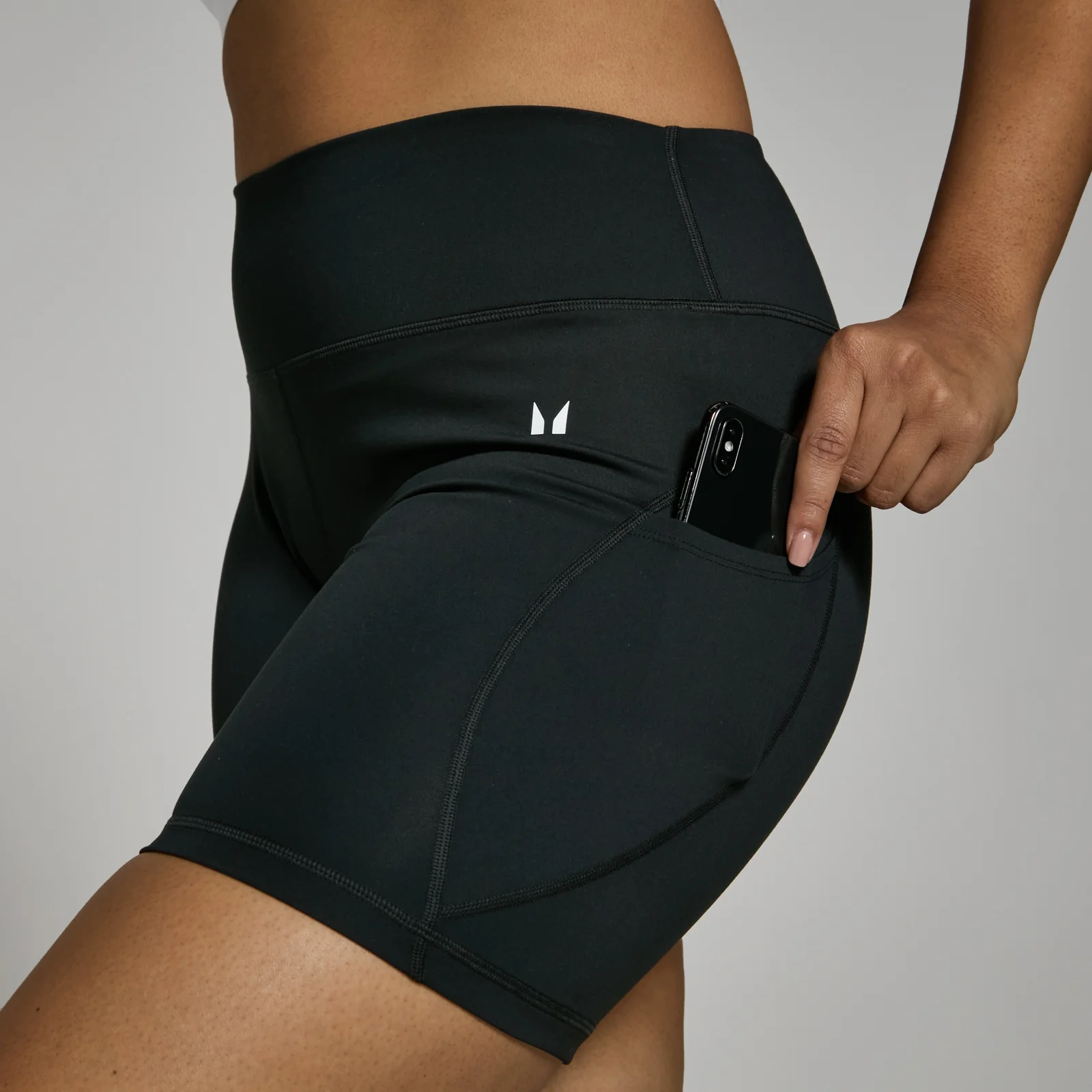 Zwarte fietsshort met hoge taille en een zak waar een telefoon in zit.