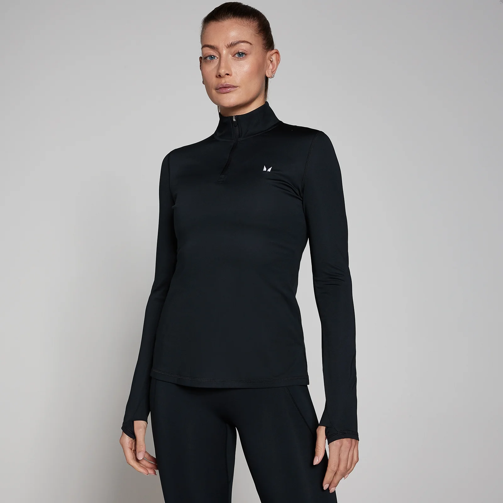 Een zwarte sporttrui met lange mouwen en een kwartrits, gedragen door een vrouw.
