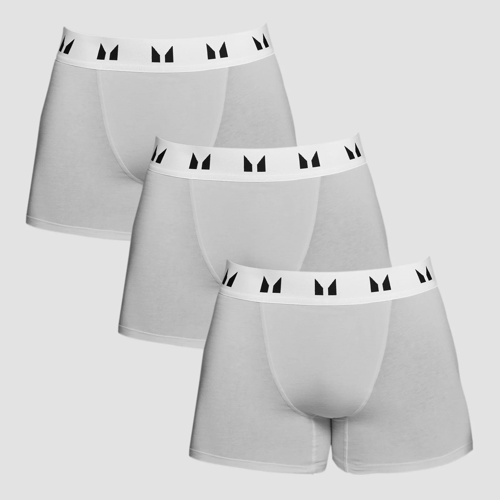 Drie grijze boxershorts met een witte band met zwarte logo's erop.