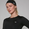 Een vrouw draagt een zwarte hoofdband met een wit logo, en een zwart shirt met lange mouwen.