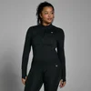 Een vrouw draagt een zwarte, aansluitende sportjas met lange mouwen en een rits.