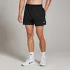 Een man draagt een zwarte MP sportshort met een wit logo, witte sokken en witte sportschoenen.