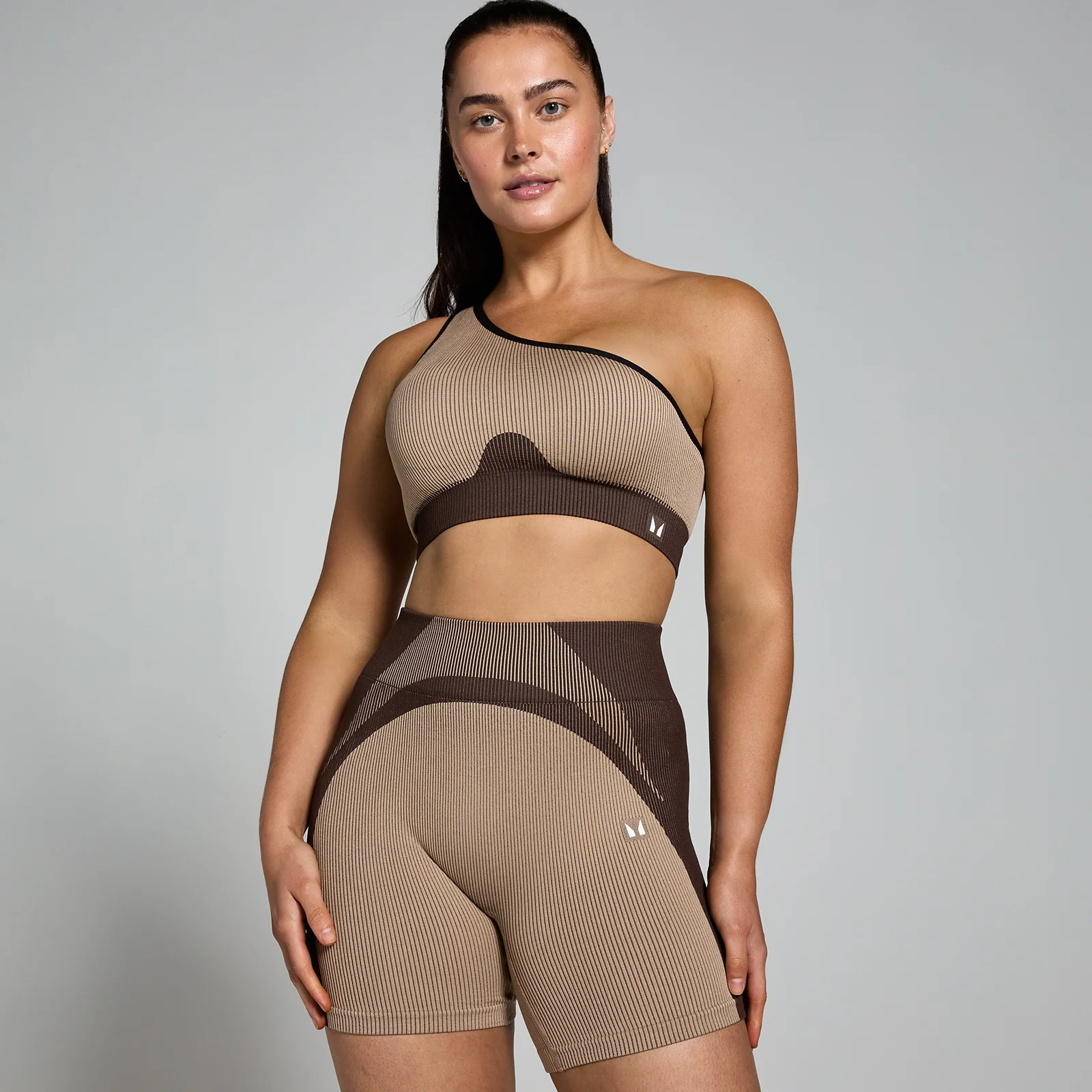 Een vrouw draagt een kasjmier/espressobruine ribstof sportbeha en bijpassende korte broek van het merk MP.