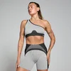 Een vrouw draagt een gestreepte, ribgebreide sportbeha met één schouderband en bijpassende korte broek.
