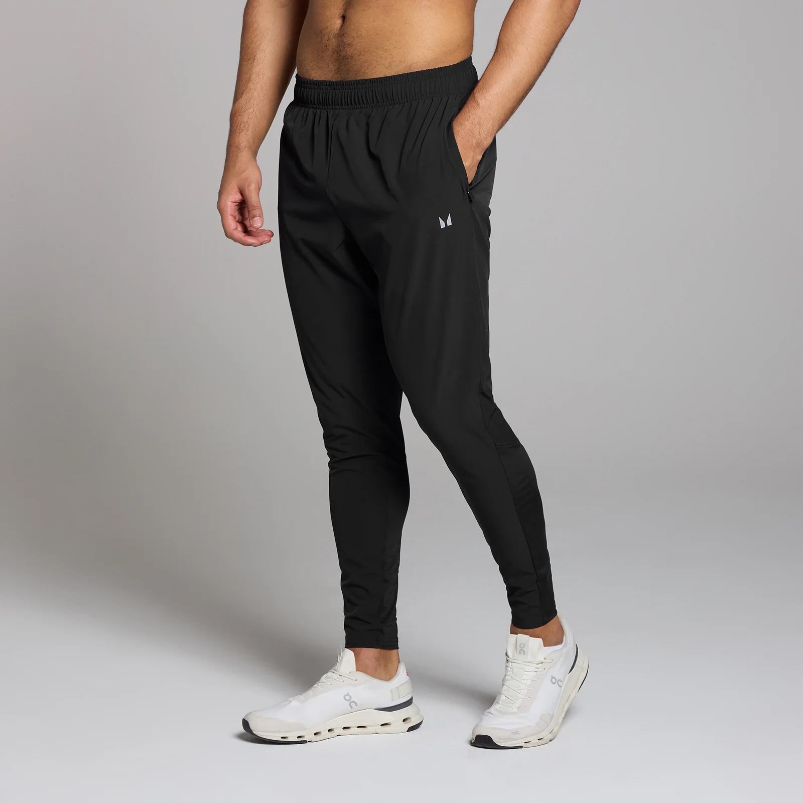 Een man draagt een zwarte MP trainingsjoggingbroek met een elastische tailleband en zakken.