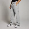 Een man draagt een gemêleerde stormgrijze joggingbroek met rechte pijpen en een wit logo.