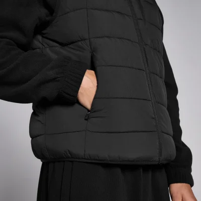 Een close-up van een zwarte, gewatteerde bodywarmer met een hand in de zak.