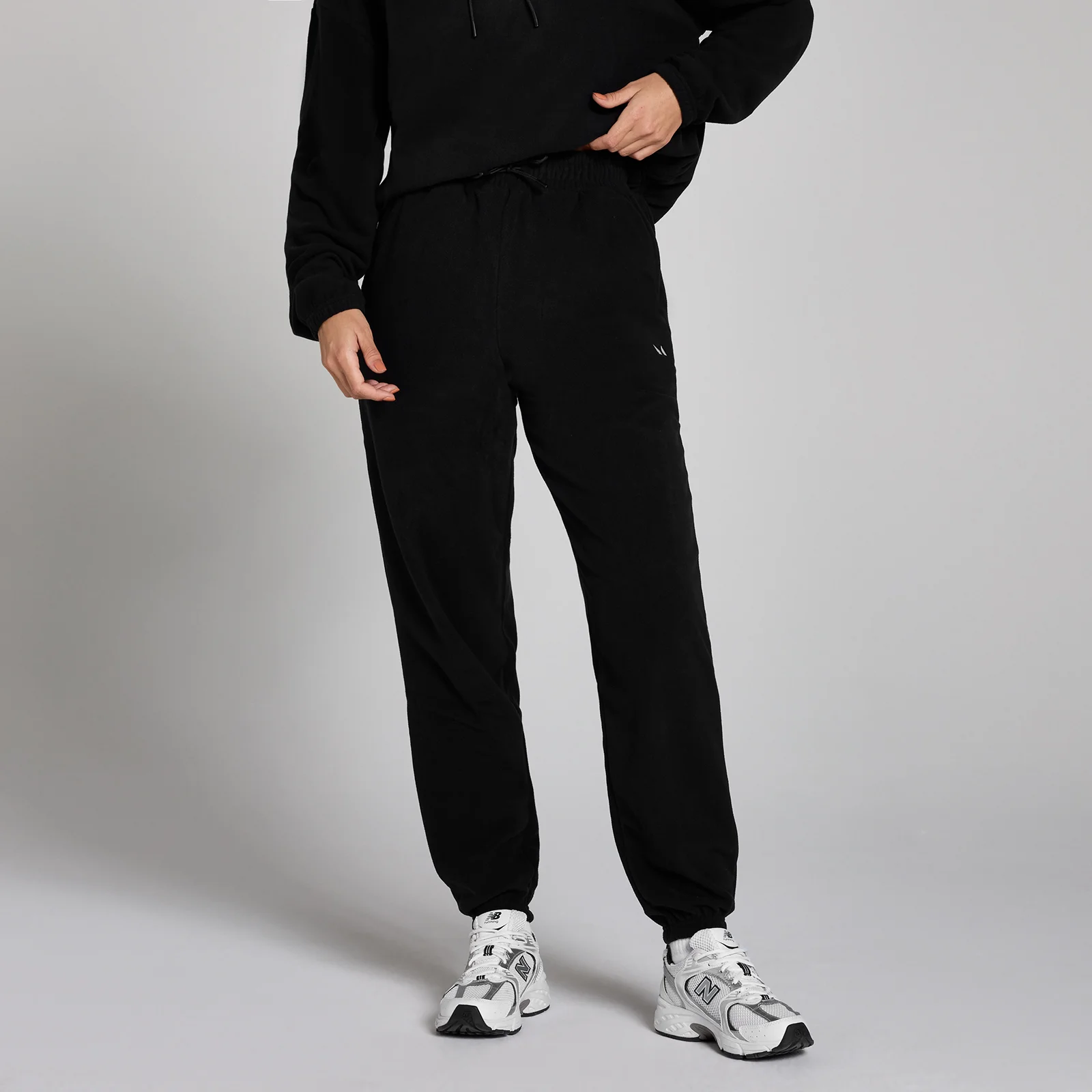 Een zwarte fleece joggingbroek met een trekkoord in de taille en elastische enkels.