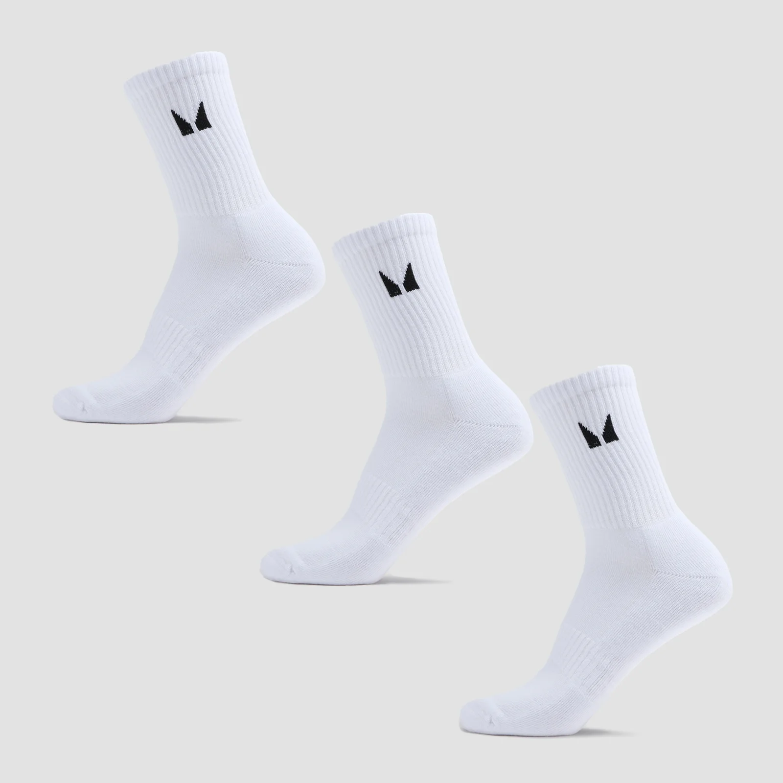 Drie witte sokken met een zwart logo, op een grijze achtergrond.