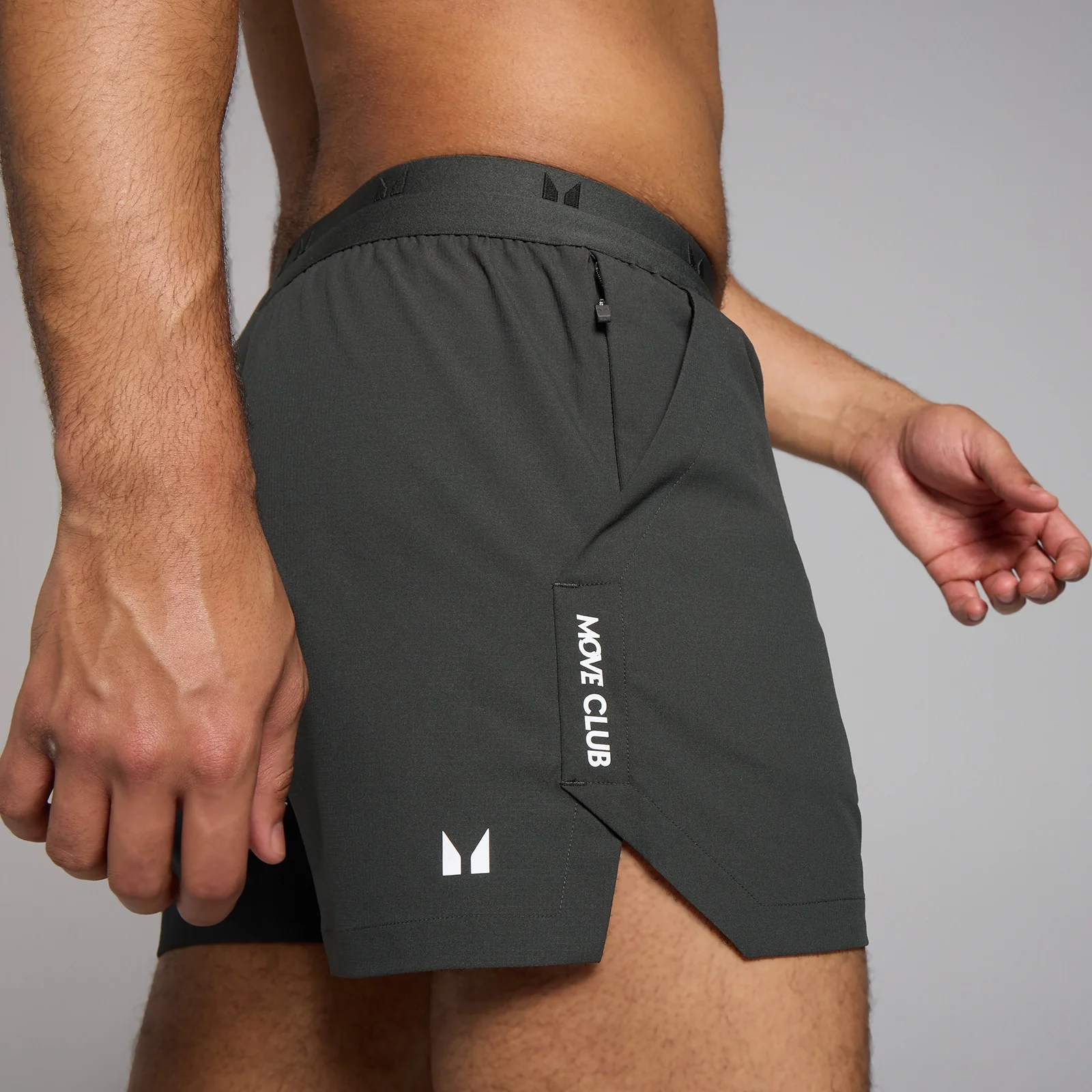 Een donkergrijze sportshort met een elastische tailleband en een witte opdruk "MOVE CLUB.