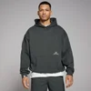 Een man draagt een oversized, verwassen zwarte hoodie met capuchon en een zak aan de voorkant.