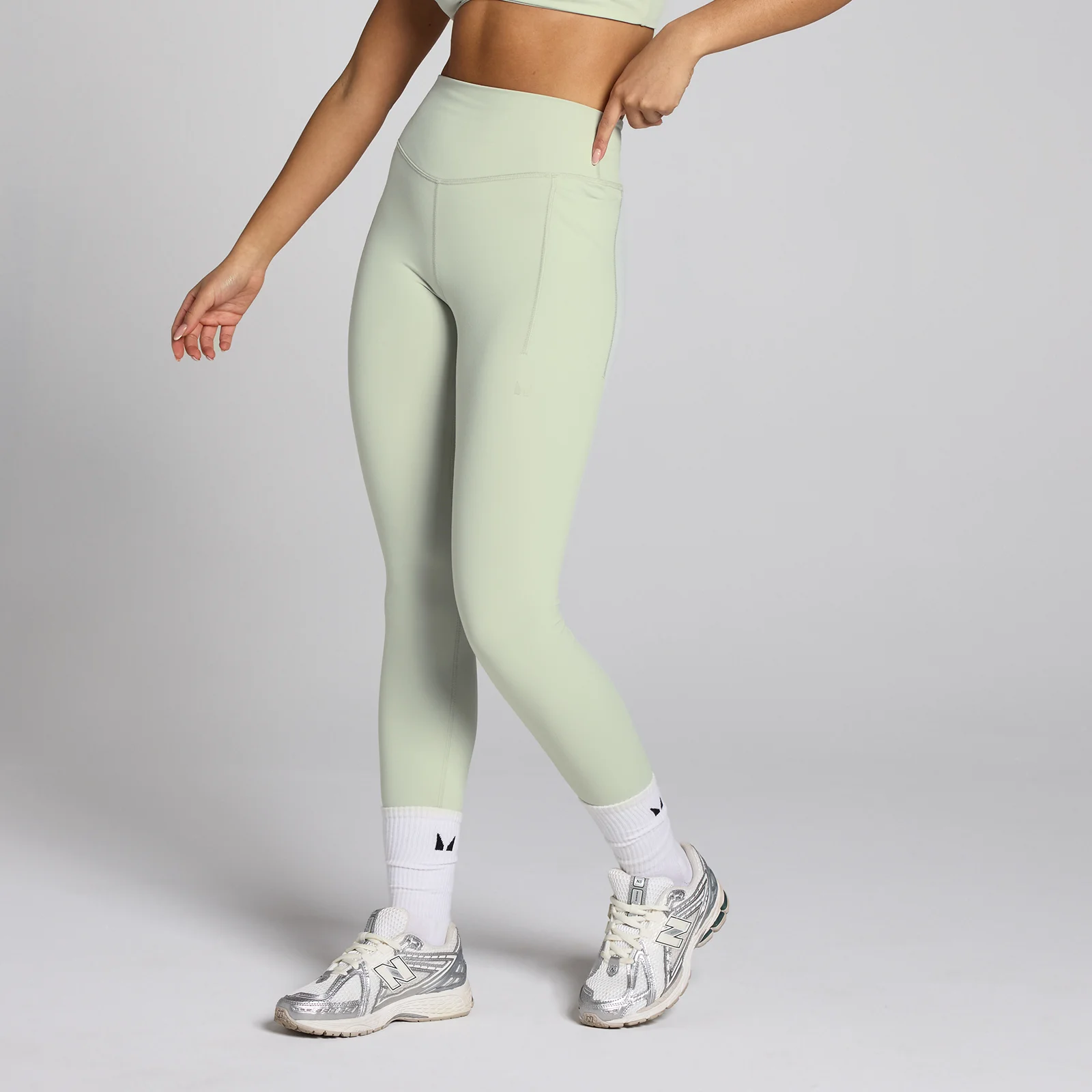 Een mineraalgroene sportlegging met hoge taille en een zak op het been.