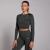 Een vrouw draagt een donkergroene, naadloze croptop met lange mouwen en een bijpassende legging.