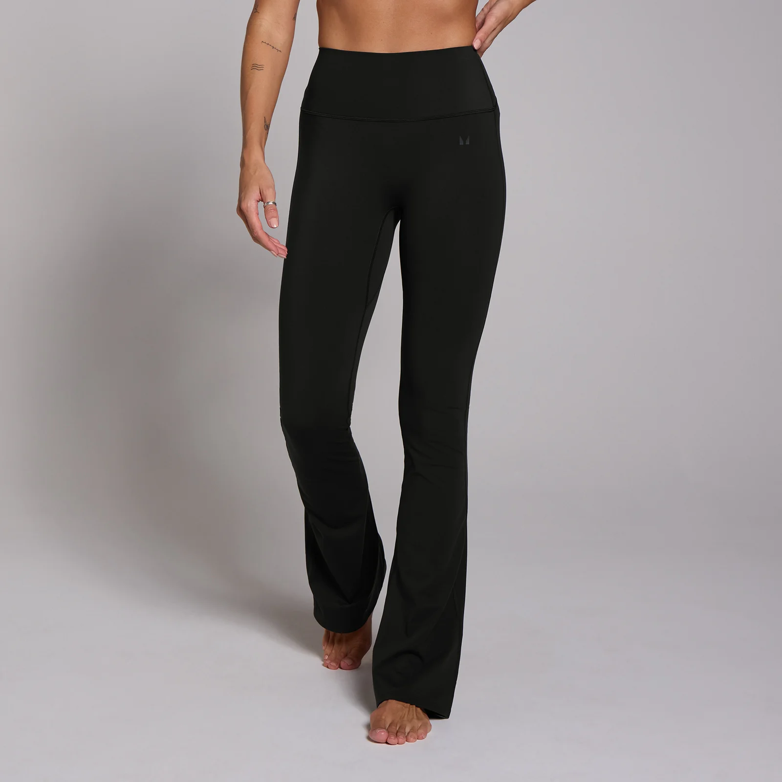Zwarte legging met hoge taille en uitlopende pijpen, gedragen door een persoon.