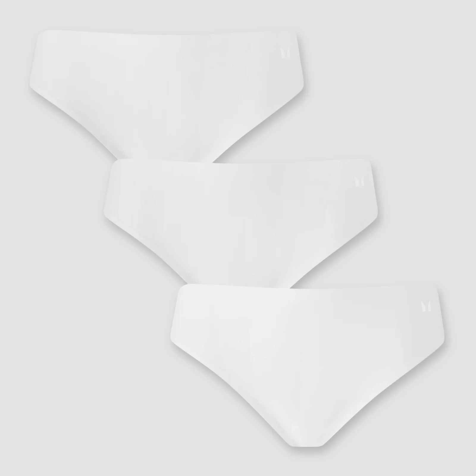 Drie witte, naadloze bikinibroekjes van MP, gestapeld op een grijze achtergrond.