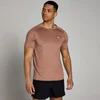 Een man draagt een bruin trainingsshirt met korte mouwen en een klein wit logo.