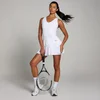 Een vrouw draagt een witte, mouwloze tennisjurk met plooien en houdt een tennisracket vast.