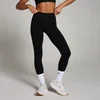 Een vrouw draagt een zwarte, naadloze legging tot de enkels, met witte sokken en sportschoenen.