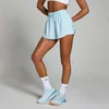 Een vrouw draagt een babyblauwe, losvallende sportshort met een elastische tailleband en bijpassende schoenen.