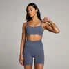 Een vrouw draagt een houtskoolblauwe sportbeha en bijpassende korte broek van het merk MP.