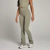Een vrouw draagt een olijfgroene legging met uitlopende pijpen en witte sneakers.