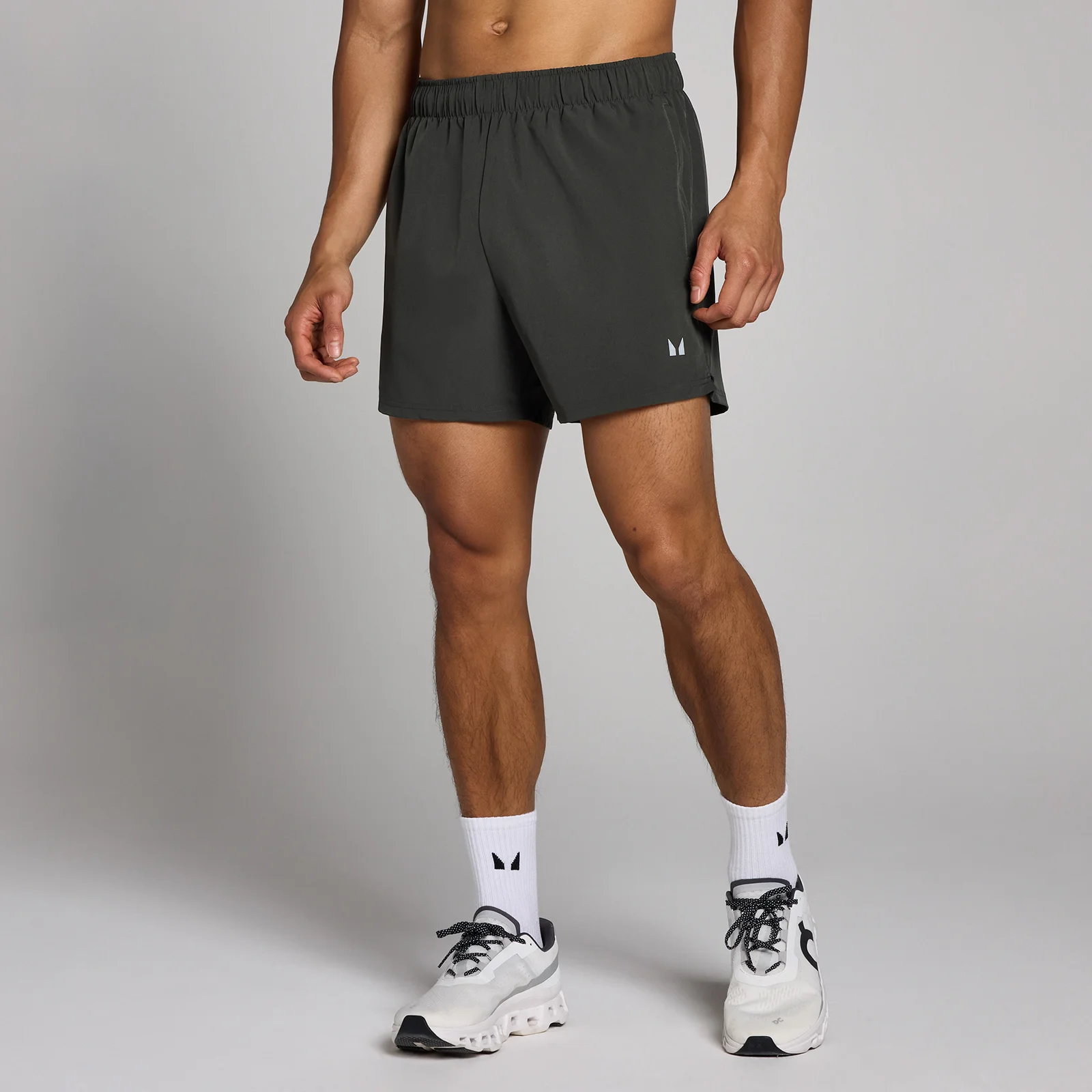 Een man draagt een verwassen zwarte, korte sportbroek met een elastische tailleband en het MP logo.